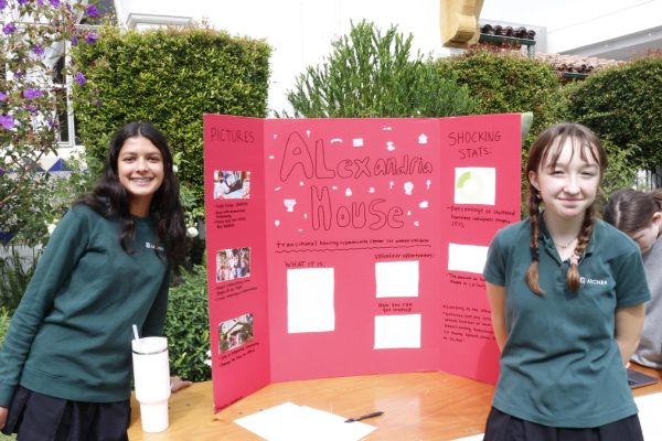 Sophomores Beatrice Washburn and Shanthi Seth stand in front of their poster for the Alexandria House, a women's shelter in Los Angeles. Students from grades 10-12 showcased the service and activism projects at the Archer in Action fair Oct. 17.