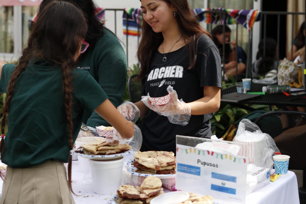 Phoebe Ramirez ('24) serves pupusa, a tortilla stuffed with ingredients such as cheese, beans and meat, which is the national food of El Salvador. The Hermanas Unidas Executive Board hosted a courtyard celebration Friday, Oct. 4 to honor Hispanic Heritage Month.