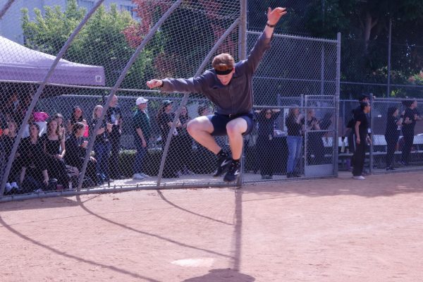 Math teacher Lucas Hoffman jumps onto home plate. scoring another home run for the faculty team. Hoffman showed off for the crowd, running to each base and occasionally doing a front flip to land on first base.