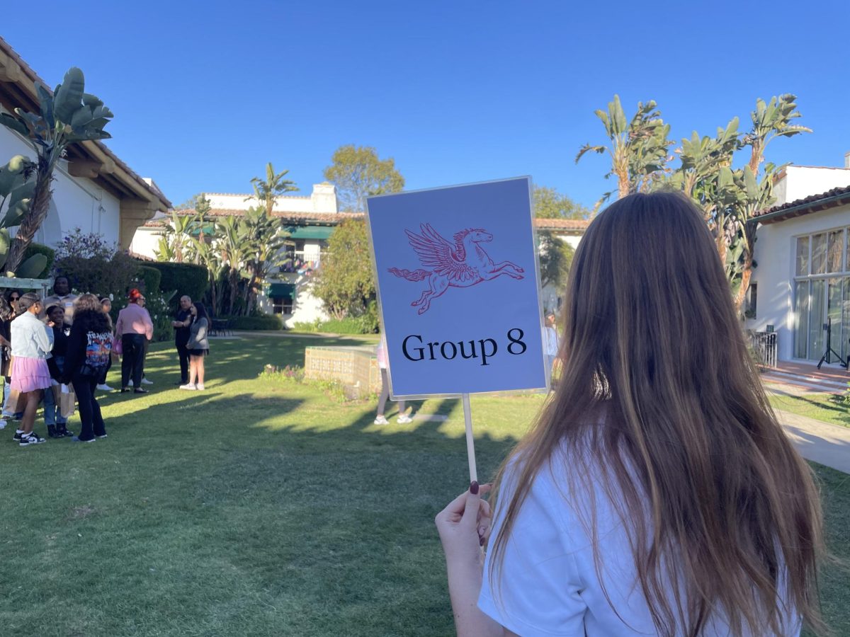 Archer Student Ari Borstein holds a sign in the middle of the courtyard. Each group had a specific Archer mascot, so applying students could find their group.