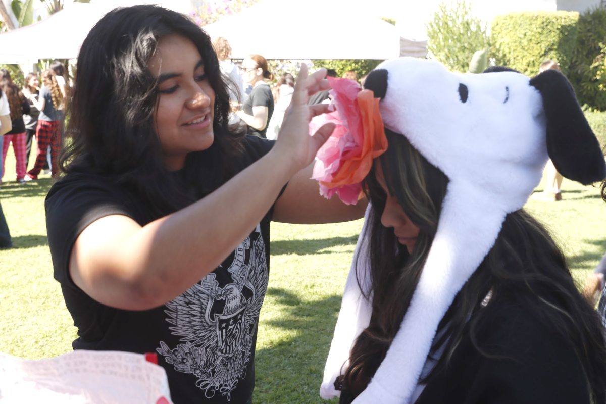 Senior Danilka Foronda Zanipatin makes a paper flower with freshman Camila Carmona Gonzalez Friday, Nov. 1, as a part of Archer's lunchtime Día de Los Muertos celebration. Paper flowers also cover Archer's ofrenda, one of many ways loved ones are celebrated on the holiday. (Photo credit: Caroline Fu)