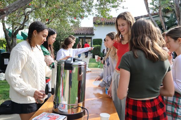 Student Council representatives Sloane Fitzgibbon ('27) and Sydney Lem ('28) serve hot chocolate in the courtyard Friday, Dec. 13. Student council held its annual Winter Wonderland, complete with gingerbread house decorating, holiday trivia and latkes. 