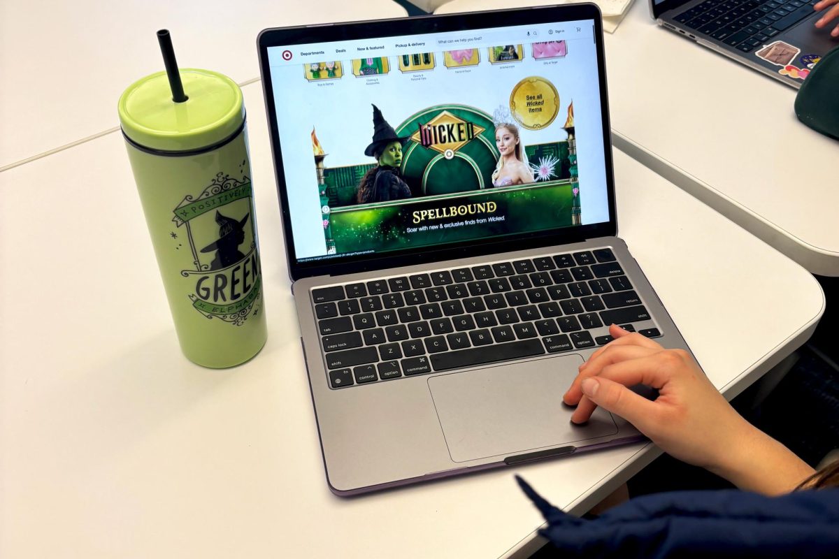 Julia Ong ('26) browses online at the Target "Wicked" merch with her "Wicked" cup from Universal City Walk. The recently released movie musical "Wicked" collaborated with over 450 brands to promote the movie. 