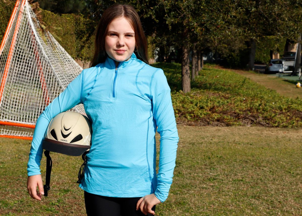 Violet Moczydlowsky (‘31) poses in her equestrian apparel, helmet in hand on Archers' back field. Moczydlowsky recently finished her first season on Archer’s new Interscholastic Equestrian League team. “That program gives you an awesome opportunity to be able to learn how to adapt quickly,” Moczydlowsky’s mother Brandi Montague said.