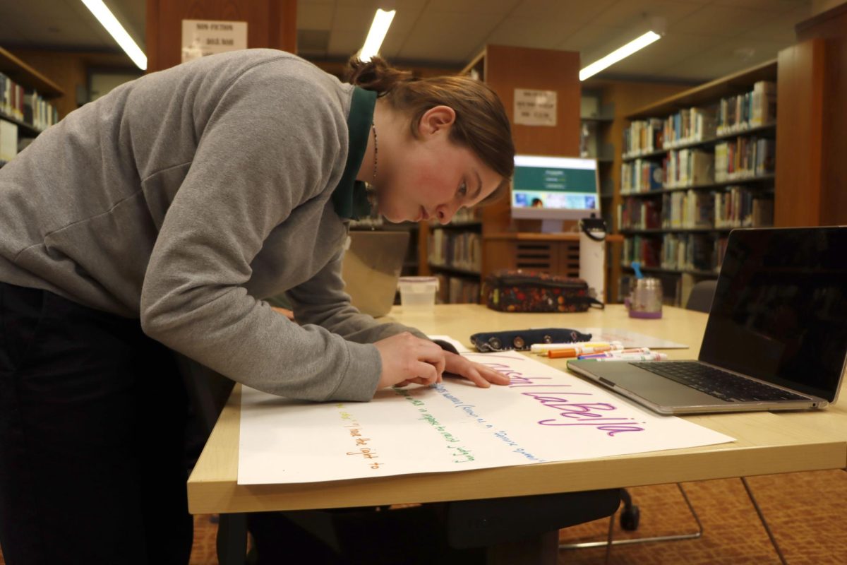 Junior Stella Leland works on a poster dedicated to transgender drag queen Crystal LaBeija. On Monday, March 3, the Gender-Sexuality Alliance club collaborated with the library to create posters of queer women in celebration of Women’s History Month.