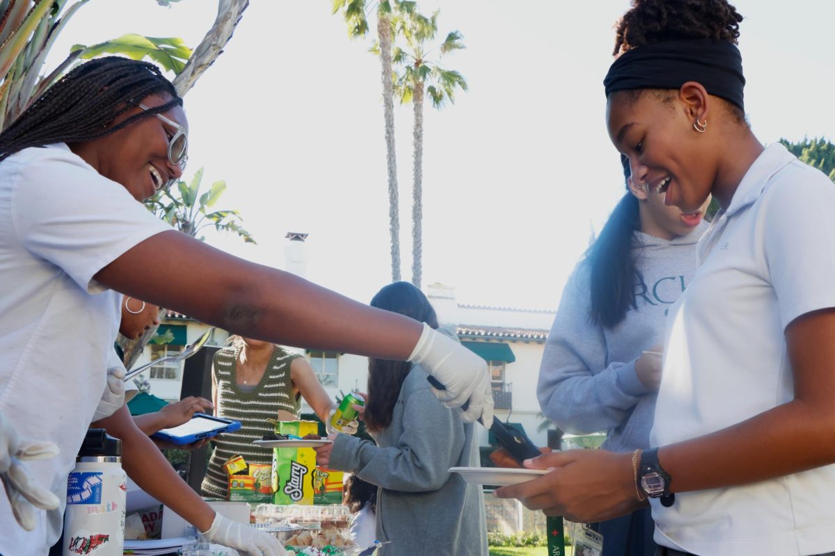 Reaching out with a piece of jerk chicken, senior Serenity Jones helps serve food at Archer's Black Student Union's fundraiser that took place Friday, Dec 12. The fundraiser was to raise money to contribute to humanitarian aid for Hurricane Melissa victims. All funds went to Project HOPE, a nonprofit, humanitarian organization actively involved in helping those affected in the Caribbean. 