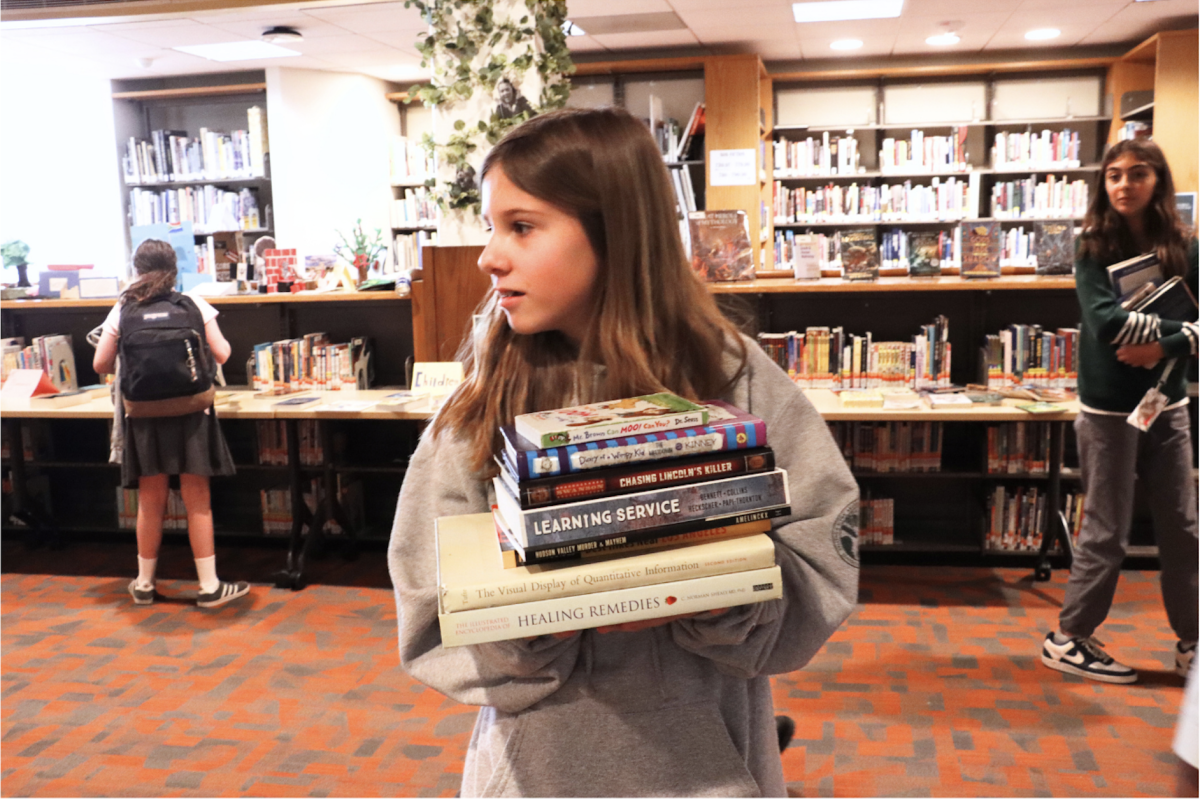 A student holds a handful of books, getting ready to check out. Many students got the opportunity to repurpose unused books they have for this event. Bratman said she likes how the book fair encourages sustainable reading practices in the Archer community. “I like the sustainability of it,” Bratman said. “I like that we're repurposing books and not just throwing them away.” 