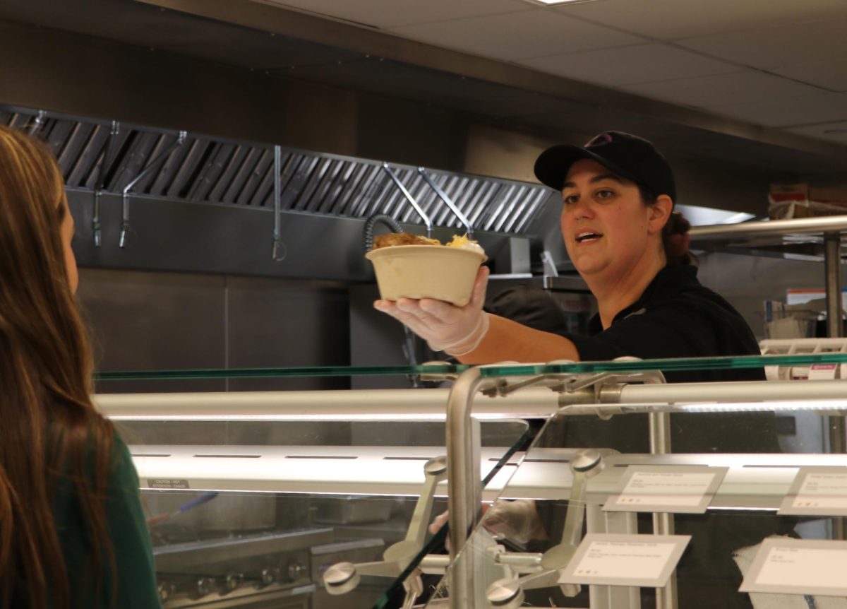 Behind the Servery’s hot-food bar, Pantry Chef Katlin Tomlin hands a student lunch. During Tomlin’s shift that day, she handed out a choice of single-serving pizzas or baked potatoes. “Archer’s cool because it's a small kitchen staff, so you kind of get to dip your toe into everything, which is really cool,” Tomlin said.
