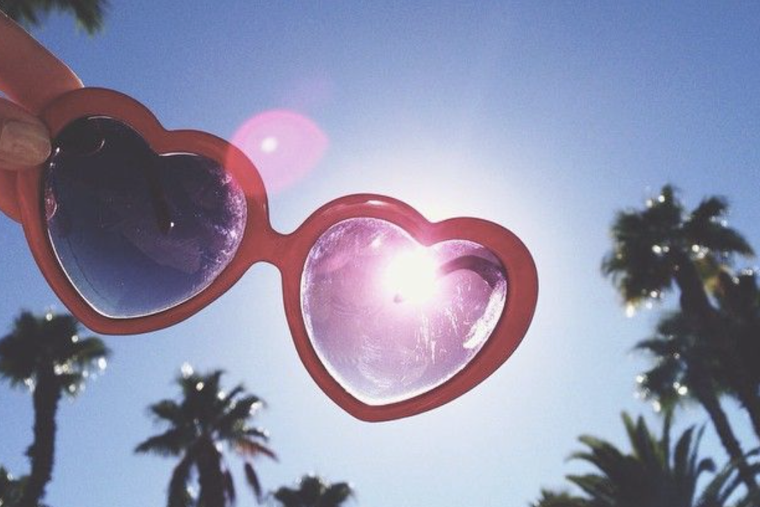 Framed by palm trees, a girl lifts heart-shaped glasses toward the sun. The year 2016 is often associated with nostalgia, happiness and serenity because many people remember it as a time that felt simpler and more carefree. (Photo courtesy of Francesca Taylor)