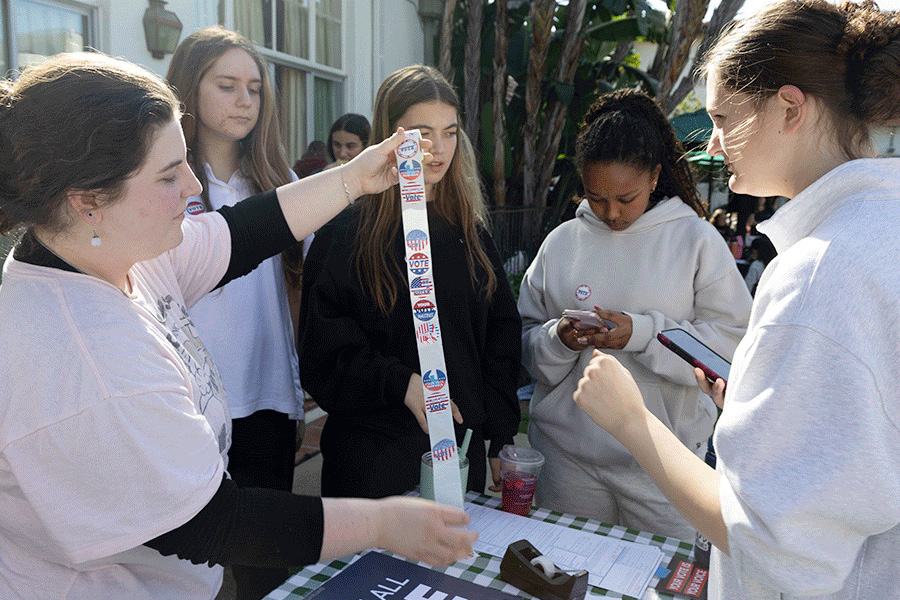 Bridgett Levy ('27) shows the plethora of democracy-inspired stickers at their call-in table to a group of students. Levy said the only way to demand change is to point out flaws in our government to elected representatives. “I think the most important part about a democracy is that it represents the people's voice," Levy said, "and sometimes our elected officials don't always represent what we want."