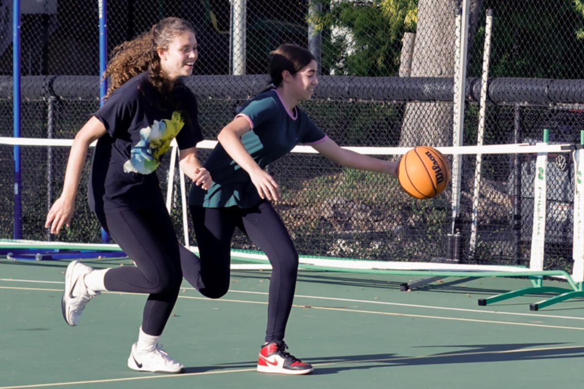 At basketball practice, Paloma Lebenzon ('27) attempts to steal the ball from Nika Honarpour ('29). They scrimmaged against each other in a one vs. one at Archer's back field. "I love the team and I love the coaches - everybody's super nice." Lebenzon said "I think our dynamic is really good."