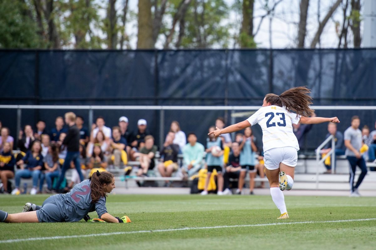 Archer's new soccer coach Brianna Atterbury runs across the grass, clad in her cleets during a game she played for  the University of Michigan. She said her goal has always been to bring a fun atmosphere to the field. "We all play because we enjoy it," Atterbury said. "So I think getting back to that on the hard days is always important and motivating as well."  (Photo courtesy of Brianna Atterbury)