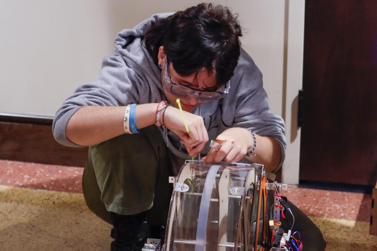 Senior Max Speck crouches over The Muse's team robot, Clementine, to secure a zip tie on it. This is his second competition on the team, and one of the largest of the season. "I think it went pretty well," Speck said. "We are not advancing. However, we aren't very angry about it."