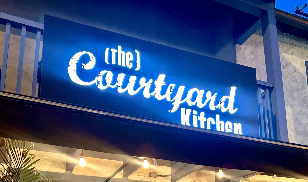 A bright, large sign for the Courtyard Kitchen illuminates the entrance of the  restaurant. At first glance, the restaurant seems subtle, but the hidden greenery conceals the warm, inviting interior inside. 
