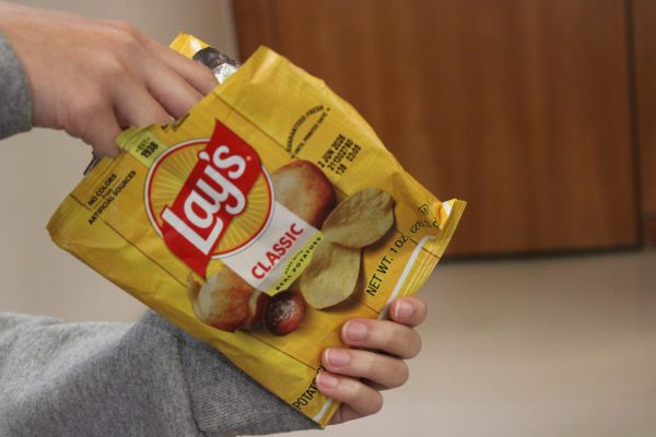 A student reaches into a Lay's Classic Potato Chips bag during lunch. 
Starting last year, the PepsiCo company has been rebranding Lay's chips visual identity in an effort to emphasize the "real potato" ingredients. Though marketing suggests that Lays chips are made solely from whole foods, nutritional science still classifies this product as ultra-processed, according to Hartford Helathcare.