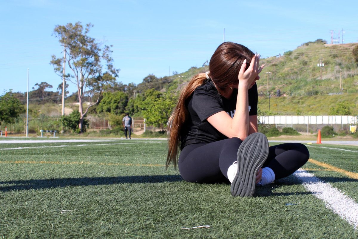 Sophie Cousens ('27) stretches with her hand on her head. Cousens is a short distance runner and competes in 100-and 200-meter races. "There is a minute when it just goes quiet. You're really not thinking of anything, and you're just trying to get to the other side of the track — it's animalistic,” Cousens said. “That's why I do track.”