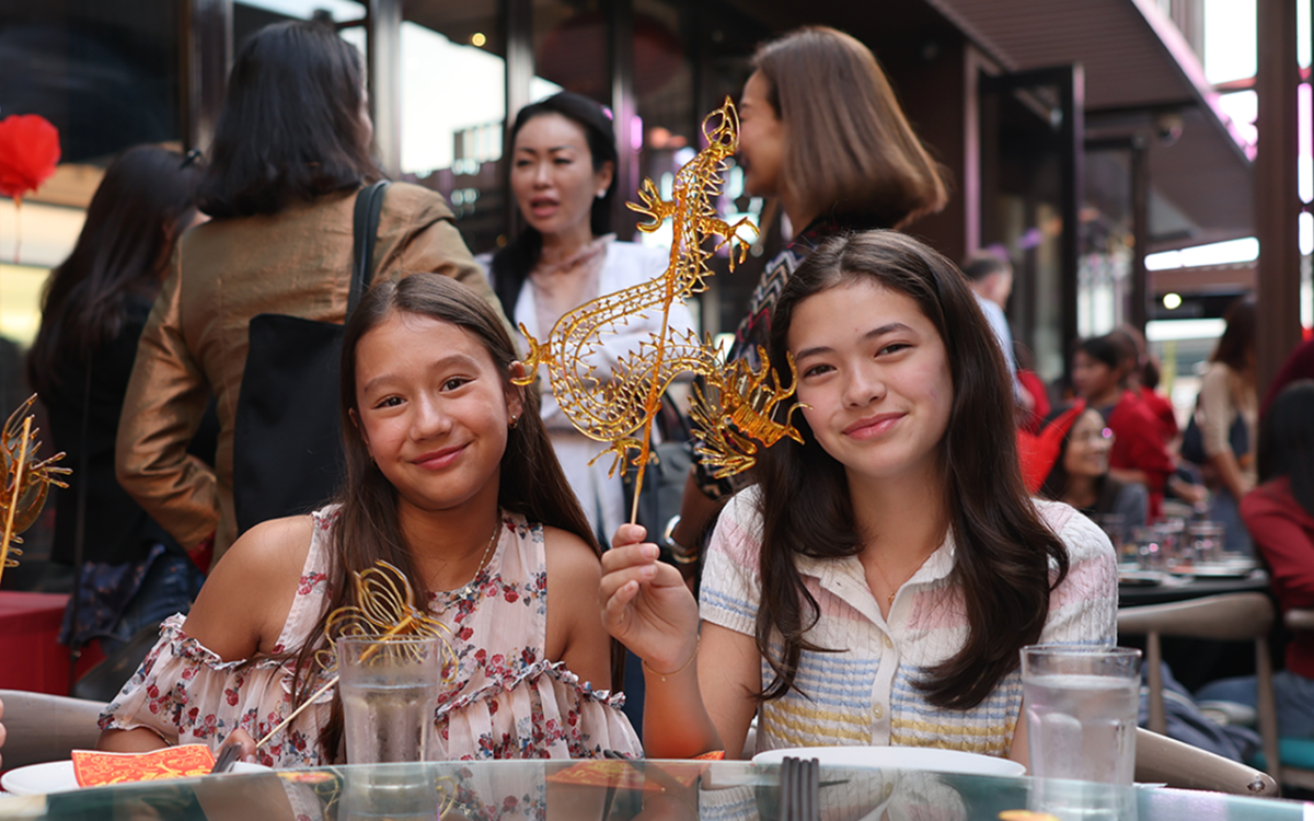 Sonoma Klungness ('32) and Coco Broccoli ('32) students hold up handmade sugar art. The sugar painter poured hot liquid sugar onto a flat surface to draw intricate designs. "I really did like it," Averie Tan ('32) said, "I especially liked watching her make the dragon; that was so cool." (Photo courtesy of Allen Ho)