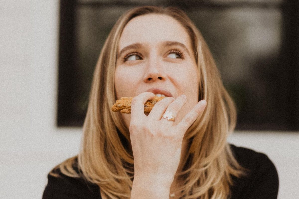 Mallory Page, RD, bites into a cookie while grinning. Page believes we should allow ourselves to follow our cravings and discover what a healthy relationship with food looks like on our own terms. To help others on their journey to food freedom, she has spearheaded inspiring programs like Live Unrestricted and Freedom from Food Noise. (Photo courtesy of Mallory Page)