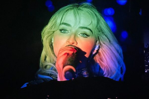Sabrina Carpenter sings during her Coachella performance as multi-colored lights shine on her face. "She had backup dancers, she had like a whole concert going on," Macy said. Macy went on to say that she thinks Carpenter had to put in more work because she's a woman. (Photo by Lucia Macy)